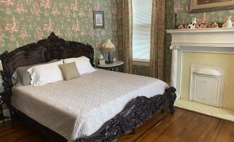a large bed with a wooden headboard and white bedding is in a bedroom with floral wallpaper at 1912 Bed and Breakfast