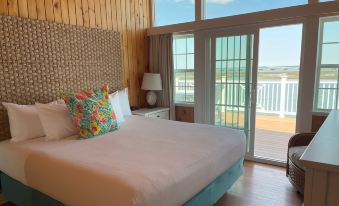 a large bed with a colorful pillow is situated in a room with wooden walls and a sliding glass door at Key West Cottages