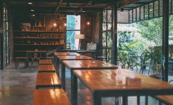 a room with wooden tables and chairs , a large window , and potted plants on the wall at Baan Rai Darun Home Stay and Scenery Raft