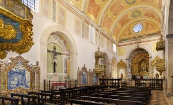 a large , ornate church with pews and crosses in a white marble room with gold accents at Convento do Espinheiro, Historic Hotel & Spa