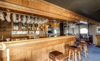 a wooden bar with a chandelier and two brown stools in front of it at Hotel Blonduos