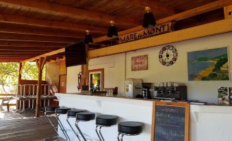 a wooden bar with several stools and chairs , as well as a chalkboard menu on the wall at Mare E Monti