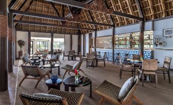 a large , open - air dining area with wooden tables and chairs arranged around a central bar at Shangri-La Yanuca Island, Fiji