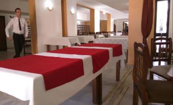 a dining room with multiple tables covered in white and red tablecloths , creating a festive atmosphere at Antar hotel