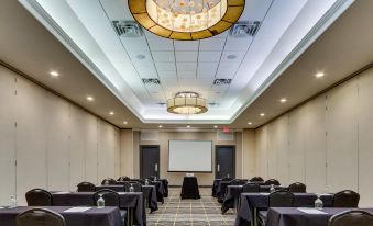 a conference room with a projector screen , chairs , and tables is set up for a presentation at Holiday Inn Staunton Conference Center