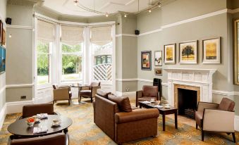 a large , elegant living room with comfortable seating , a fireplace , and framed art on the walls at Mercure Hull Grange Park Hotel