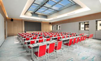 In a spacious room, rows of tables are arranged in front, while the back wall remains empty at Holiday Inn Shanghai Nanjing Road