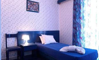 a small bedroom with a single bed , a nightstand , and a lamp on the wall at Argo Spa Hotel