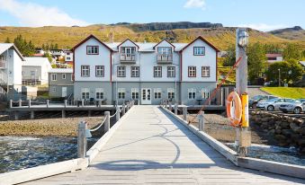 a wooden pier extending into a body of water , with a white building in the background at Fosshotel Eastfjords