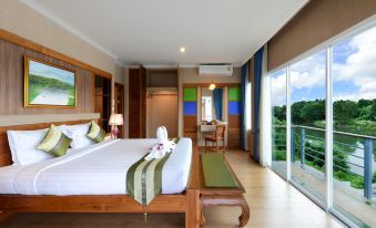 a large bed with a green canopy is in a room with wooden floors and a view of the mountains at Princess River Kwai Hotel
