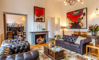 a living room with a brown leather couch , a fireplace , and several paintings on the wall at Fletcher Hotel Paleis Stadhouderlijk Hof