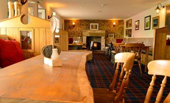 a cozy dining room with a fireplace and a long wooden table , creating a warm and inviting atmosphere at The Twice Brewed Inn