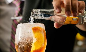 a bartender is pouring a drink into a glass filled with ice and garnished with orange slices at Crowne Plaza Dublin - Blanchardstown