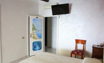 a bedroom with a bed , chair , and television mounted on the wall , along with a door leading to another room at Leonardo's