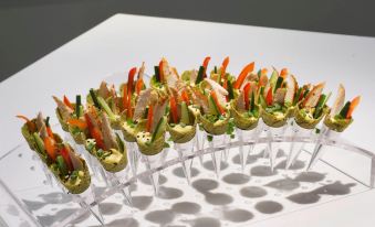 a clear plastic tray filled with an assortment of food , including chicken and vegetables , on a white table at Novotel Montreal Center