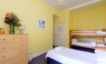 a yellow bedroom with a bed and a bunk bed , as well as a dresser and a chair at Driftwood