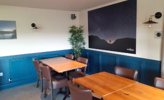 a room with blue walls and a wooden table surrounded by chairs , and a large screen on the wall at The Twice Brewed Inn