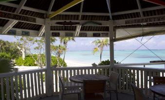 a wooden deck overlooking the ocean , with a table and chairs set up for outdoor dining at Pelican Beach Hotel