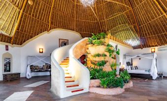 a modern interior with a thatched roof , white walls , and green plants , as well as a staircase leading to an entrance at Chale Island Resort