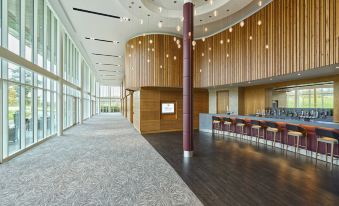 a modern hotel lobby with a long hallway , wooden columns , and a bar area , providing a comfortable and inviting atmosphere at Hilton at St.George's Park, Burton Upon Trent