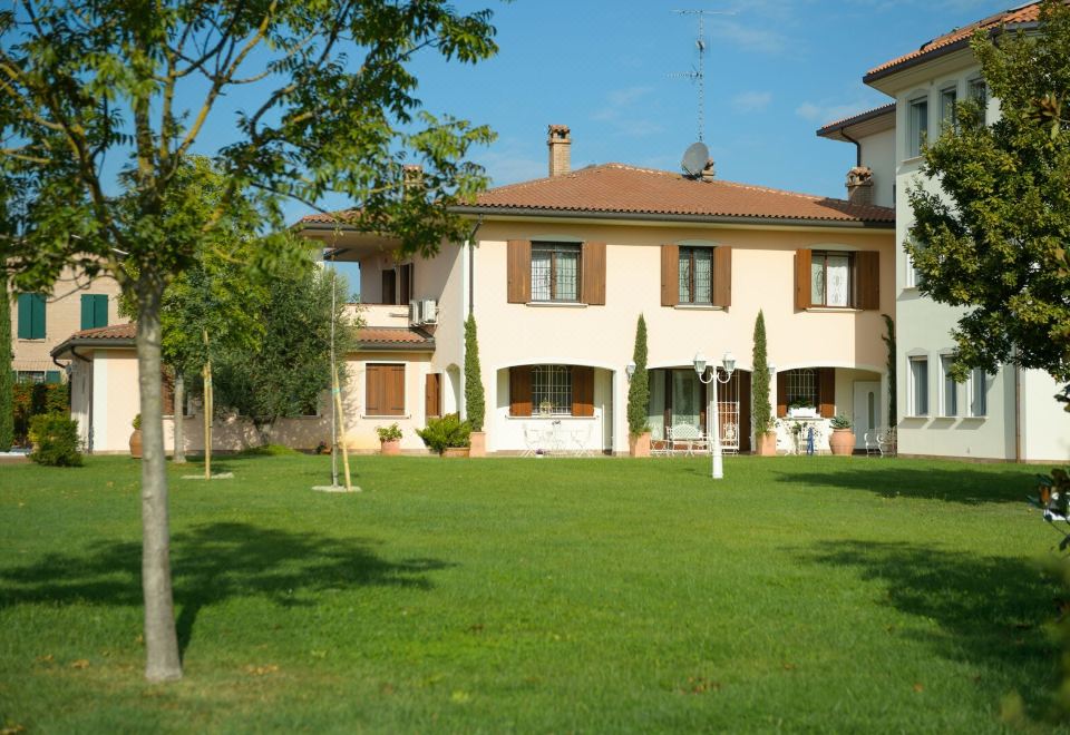 a large , two - story house with a brown roof and white walls , surrounded by green grass and trees at Hotel San Giovanni