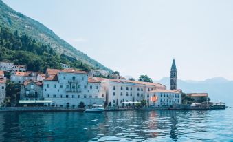 a large white building with a clock tower is situated on the shore of a body of water at Heritage Grand Perast by Rixos