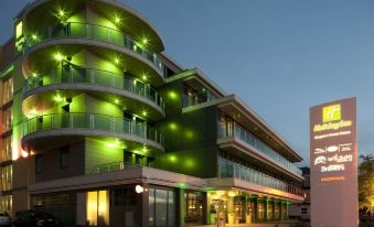 a modern building with green lights illuminating the exterior at night , creating a green glow on the street below at Crowne Plaza London - Kingston