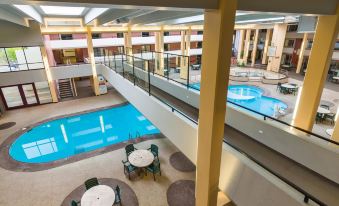 an indoor swimming pool area with multiple pools and lounge chairs , surrounded by a building at Grand Hotel