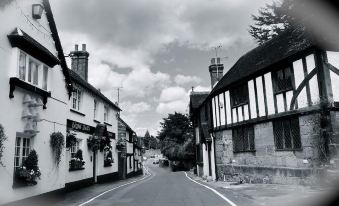 a black and white photo of a street with buildings on both sides , and a clock tower in the background at The Eight Bells