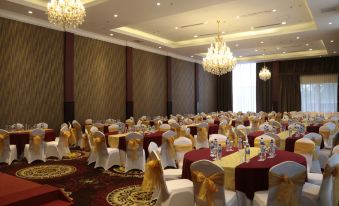a large banquet hall with tables covered in red and white tablecloths , gold chairs , and chandeliers hanging from the ceiling at Java Palace Hotel