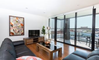 a spacious living room with hardwood floors , a large flat - screen tv mounted on the wall , and a glass door leading to a balcony at The Penthouse