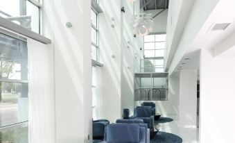 "a modern office building lobby with blue chairs , large windows , and a glass wall , under the brand name "" office one ""." at Delta Hotels by Marriott Milwaukee Northwest