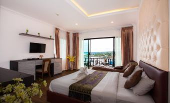 a bedroom with a large bed , a desk , and a window overlooking the ocean at night at Samprasob Resort