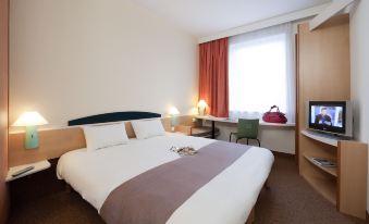 a hotel room with a bed , nightstands , and a window , along with various amenities such as lamps and curtains at Ibis Luxembourg Sud