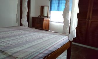 a bed with a striped blanket and white curtains is in a room next to a window at Blue Rooms