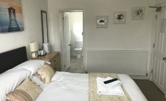 a cozy bedroom with a white bed , a dresser , and a door leading to a bathroom at Stanley Arms Hotel