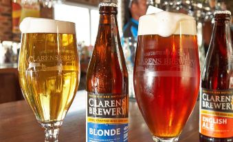"a bar with several bottles of beer , including one labeled "" clarene beer ,"" and several glasses filled with different types of beer" at Upper House Guesthouse