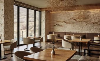 a modern restaurant with wooden tables , chairs , and a large window overlooking a mountainous landscape at The Lodge at Blue Sky, Auberge Resorts Collection