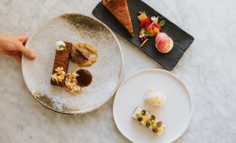 a table is set with plates of desserts , including a chocolate dessert and a slice of cake at Healing Manor Hotel