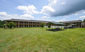 a large , brown building with a green roof is surrounded by a grassy area and trees at Americas Best Value Inn Canton