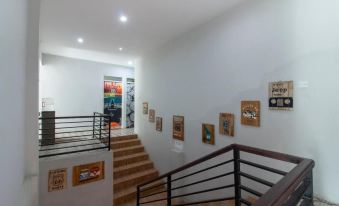 a staircase with a black railing and white walls is adorned with framed pictures on the wall at Bwalk Hotel Malang