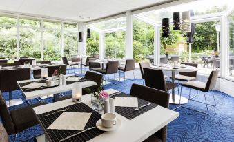 a large dining room with numerous tables and chairs arranged for a group of people to enjoy a meal together at Novotel Maastricht