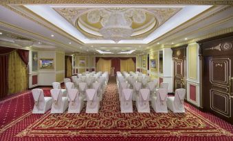 a large , ornate room with a red and gold carpet has rows of chairs arranged in a row at Royal Rose Abu Dhabi