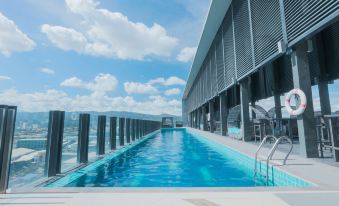 a long , narrow swimming pool is situated on a balcony with a view of the ocean at bai Hotel Cebu