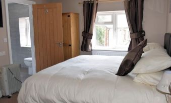 a bedroom with a large bed , white sheets , and curtains near a window that offers a view of the outdoors at The Red Lion