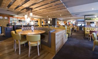 a restaurant with wooden tables and chairs , a bar , and a kitchen in the background at Premier Inn Ware
