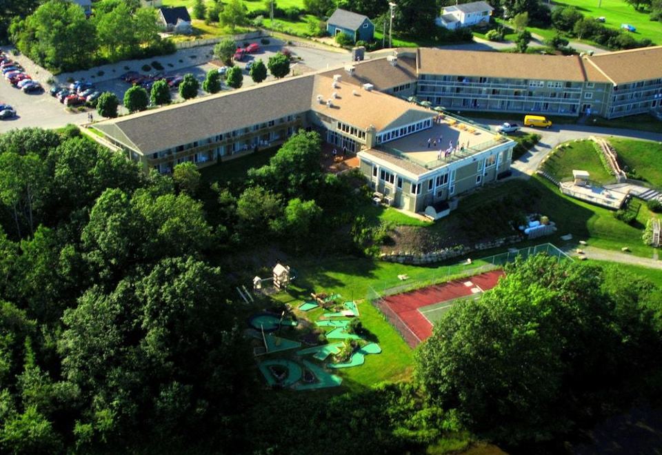 an aerial view of a large building surrounded by trees , with a playground in the foreground at Oak Island Resort & Conference Centre