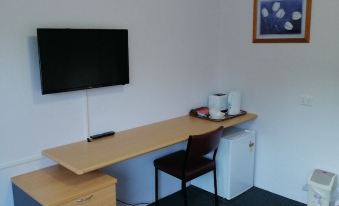 a small room with a desk , a chair , and a tv mounted on the wall at Mount Beauty Motor Inn