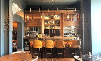 a well - stocked bar with wooden furniture , including stools and tables , along with bottles and glasses at Angel Hotel