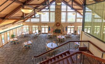 an interior view of a large room with wooden tables and chairs , large windows , and a balcony at Dale Hollow Lake State Resort Park